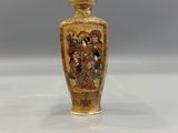 a gold vase with a painting on it sitting on a table