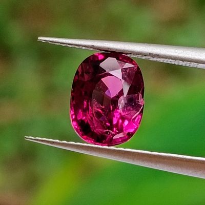 purple gems are being held by a pair of pliers on a green background