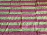 une nappe à motifs roses et verts sur laquelle est assis un chat