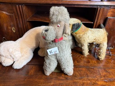 Plusieurs peluches sont posées sur un parquet, à côté d'une commode.