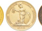 trois médailles d'or sur lesquelles figurent l'image d'une femme et celle d'un homme