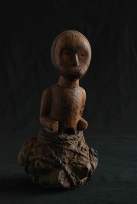 une figurine en bois posée sur un morceau de bois