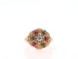 a close up of a gold ring with green and red stones