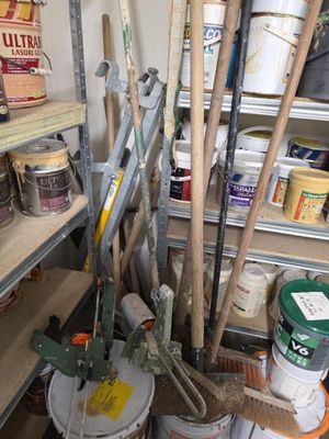 Plusieurs seaux de peinture et des outils sont posés sur une étagère
