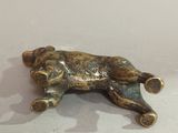 a bronze figurine of a dog laying down on a table