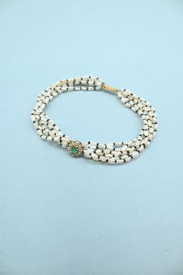 a white beaded bracelet with a gold clasp and a green stone bead