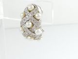an image of a white pearl and diamond ring on a clear surface