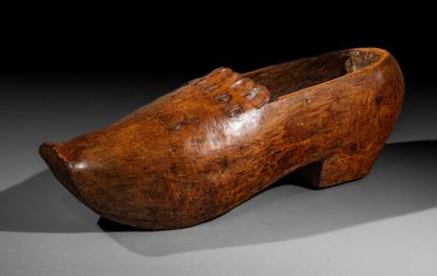 an old wooden shoe is sitting on a black surface