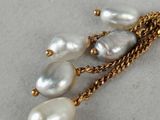 pearl and gold chain necklace with dangling pearls on a white surface
