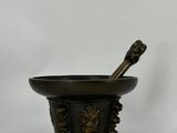 a black and gold mortar with a spoon in it