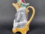 a ceramic figurine of a man sitting on a chair