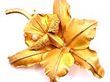 broche en forme de fleur en or, ornée de perles et de feuilles sur fond blanc