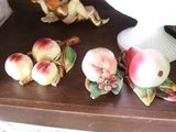 several figurines on a wooden shelf with a white vase in the background