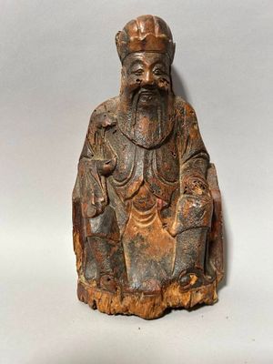 une vieille statue en bois représentant un homme barbu coiffé d'un chapeau