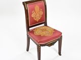 une image représentant une chaise dont l'assise est recouverte d'un tissu rouge et or