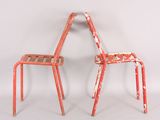 pair of red metal chairs against a white background