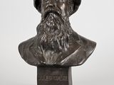 un buste en bronze représentant un homme barbu coiffé d'un chapeau