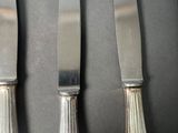 four silverware knives and a knife on a black surface
