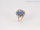a close up of a ring with a blue stone surrounded by diamonds