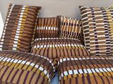de nombreux coussins disposés sur un canapé à motifs marron et blancs