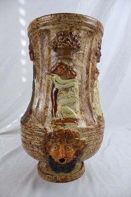 un vase marron orné d'un visage sur fond blanc