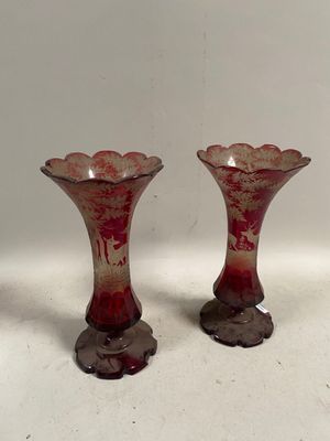 une paire de vases en verre rouge posés sur une table blanche