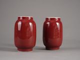 une paire de vases rouges posés sur une surface grise