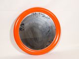 un miroir rond orange accroché à un mur blanc