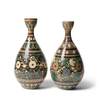 une paire de vases décoratifs posés l'un à côté de l'autre sur une surface blanche