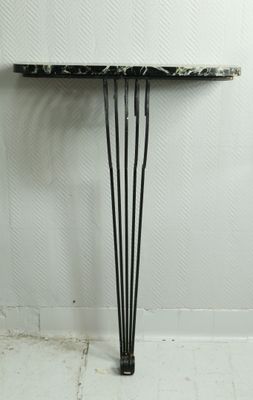 une table en marbre noir et blanc avec des pieds en épingle à cheveux dans une pièce