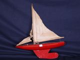 un voilier rouge avec une voile blanche sur fond bleu