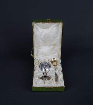 a silver spoon and spoon rest in a green box on a black background