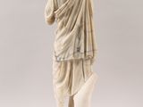 an antique statue of a man holding a book in his hands