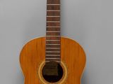 a close up of a small wooden guitar on a gray surface