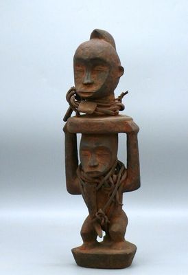 an old wooden statue of a man holding a bird on his head