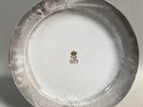 une assiette blanche ornée d'un emblème doré
