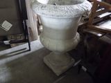 un grand vase blanc posé sur un socle dans une pièce