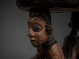a wooden sculpture of a man holding a wooden table