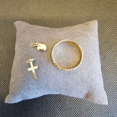 une bague, une croix et une bague posées sur un coussin