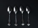 four spoons are lined up in a row on a black surface