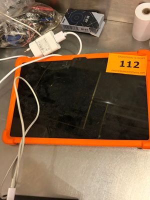une tablette orange posée sur un comptoir, à côté d'un rouleau de papier toilette