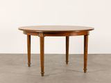 a round dining table with four legs and a wooden top