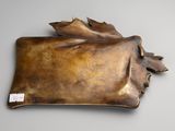 an image of a bronze sculpture of a leaf on a gray surface