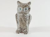 a silver owl figurine with green eyes on a white background