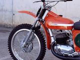 an orange dirt bike parked in front of a white wall