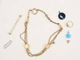 a close up of a gold chain bracelet with a blue glass pendant