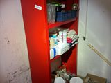 une armoire rouge dans un coin d'une pièce, sur laquelle sont posés de nombreux objets