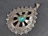 une image représentant un pendentif en argent orné d'une pierre turquoise au centre