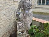une statue représentant une femme tenant un bébé dans un jardin
