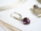 a close up of a necklace with a purple stone on it